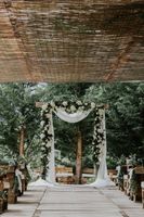 A rustic wooden wedding arch with white flowers and fresh greens