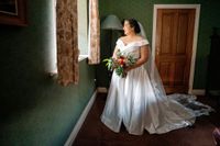 Bride holding her bouquet and looking out on a window during the photoshoot of her elopement in Ireland