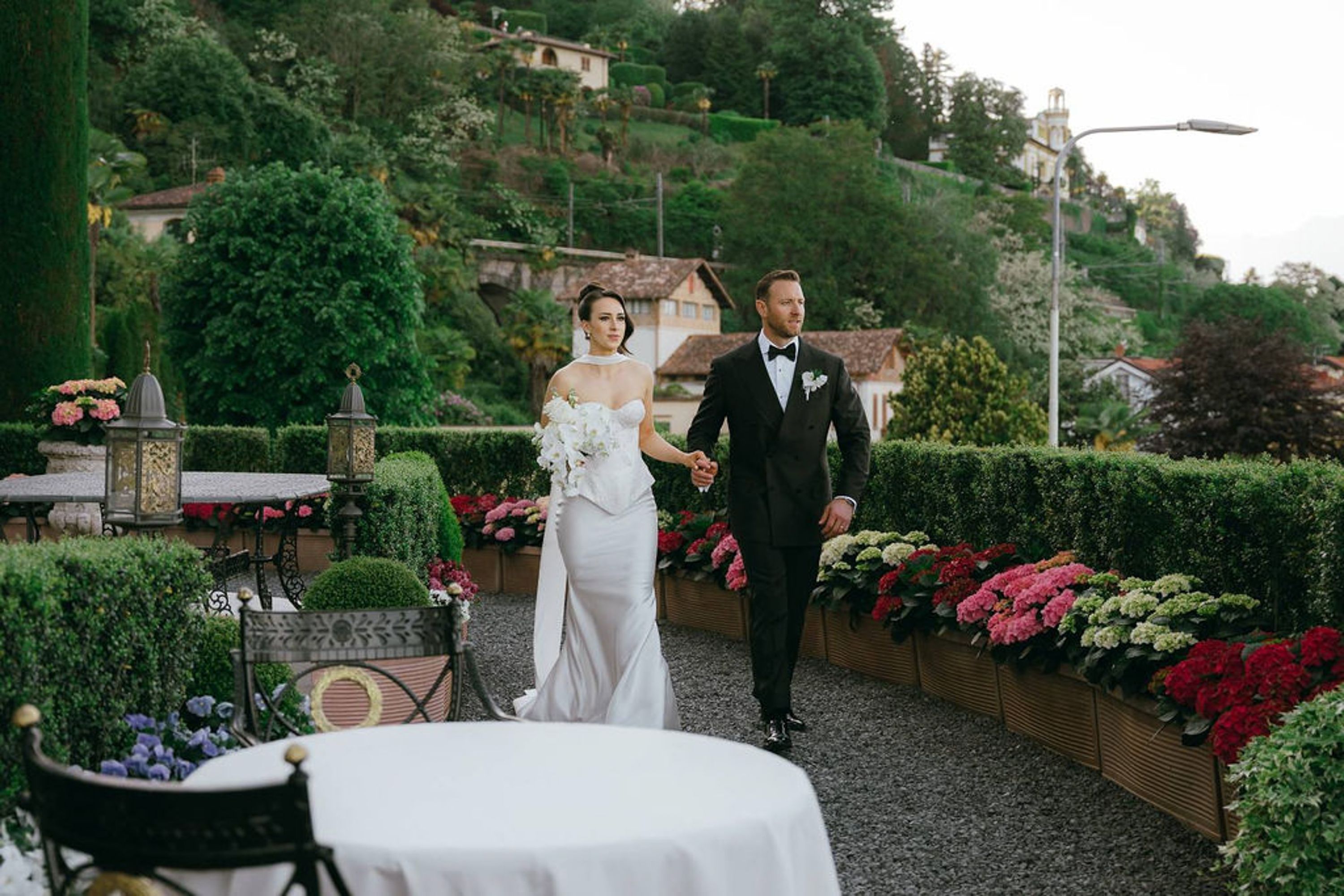 Bride and groom walking through a flower-filled garden after their small wedding in Italy