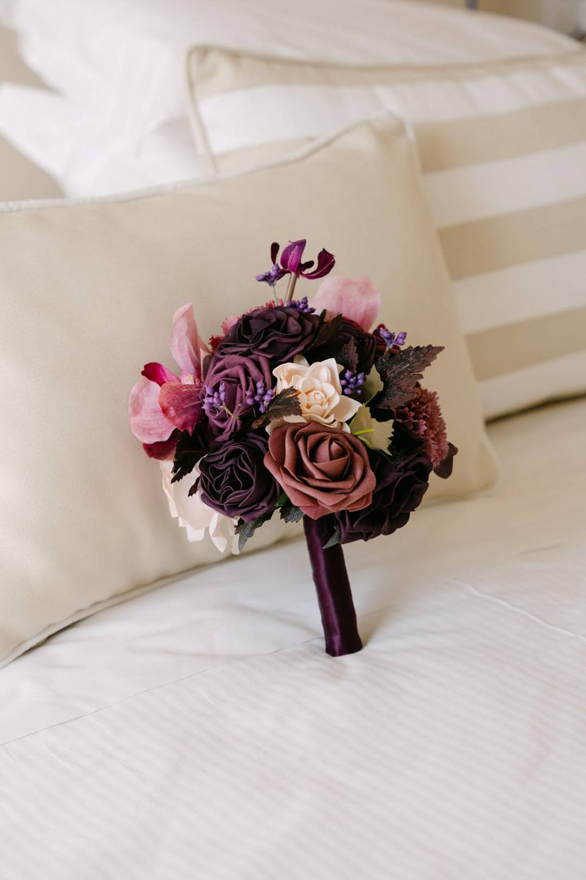 Purple and blush bridal bouquet resting on a bed before an intimate wedding in Italy