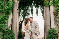 Newlyweds kissing each other with tall trees in the background during their small wedding in Italy