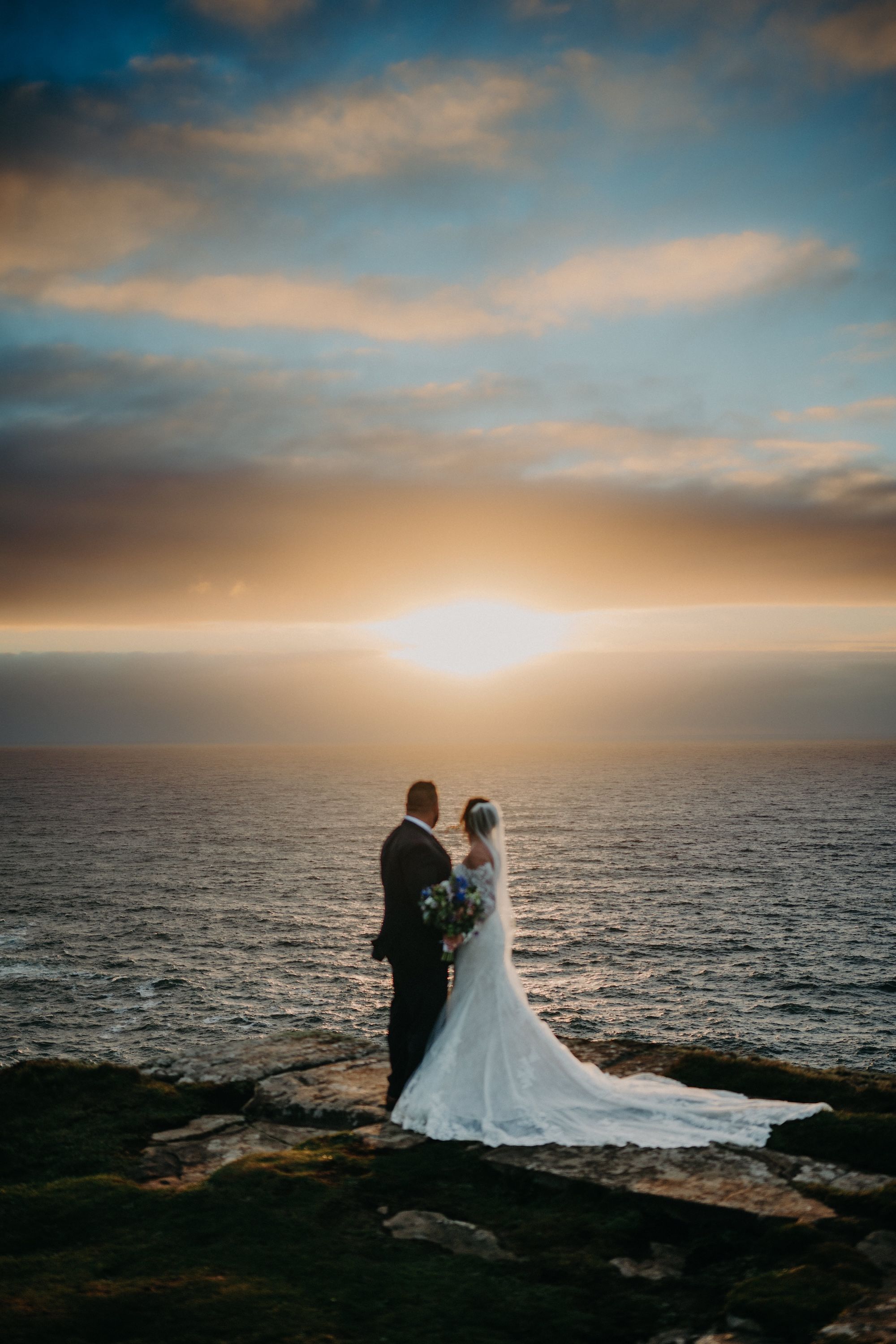 Bride and groom looking at the horizon during the photoshoot of their clifftop micro wedding in Ireland