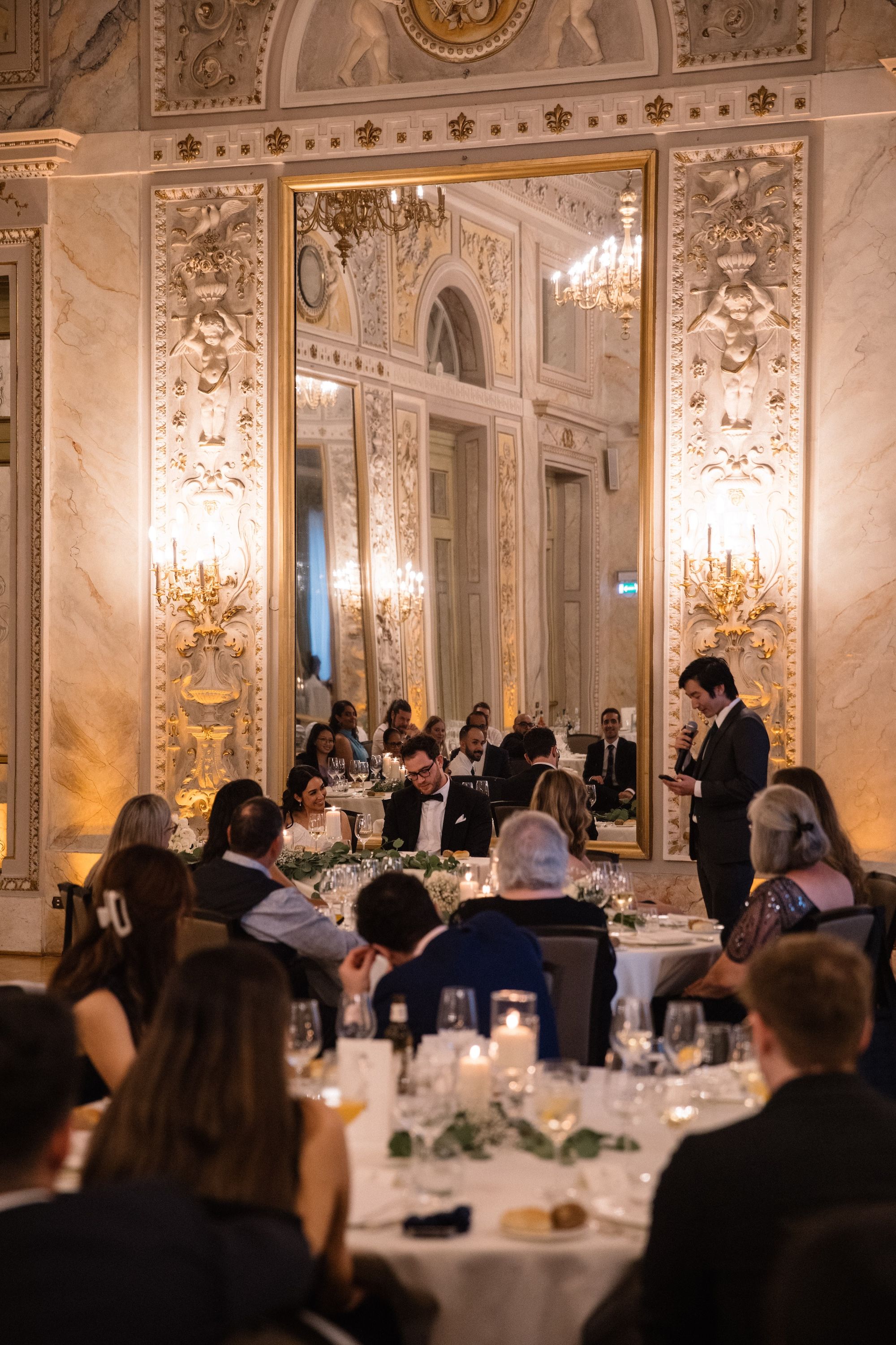 Bride, groom, and their guests listen to a speech during the dinner reception of their vow renewal in Italy