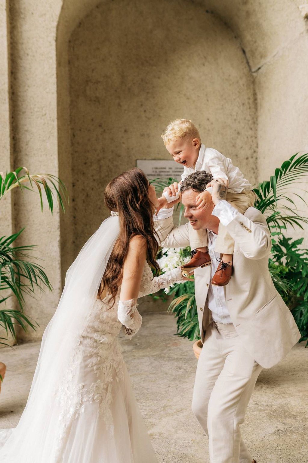 Bride and groom with their little one playing and having fun during the photoshoot of their intimate wedding in Italy