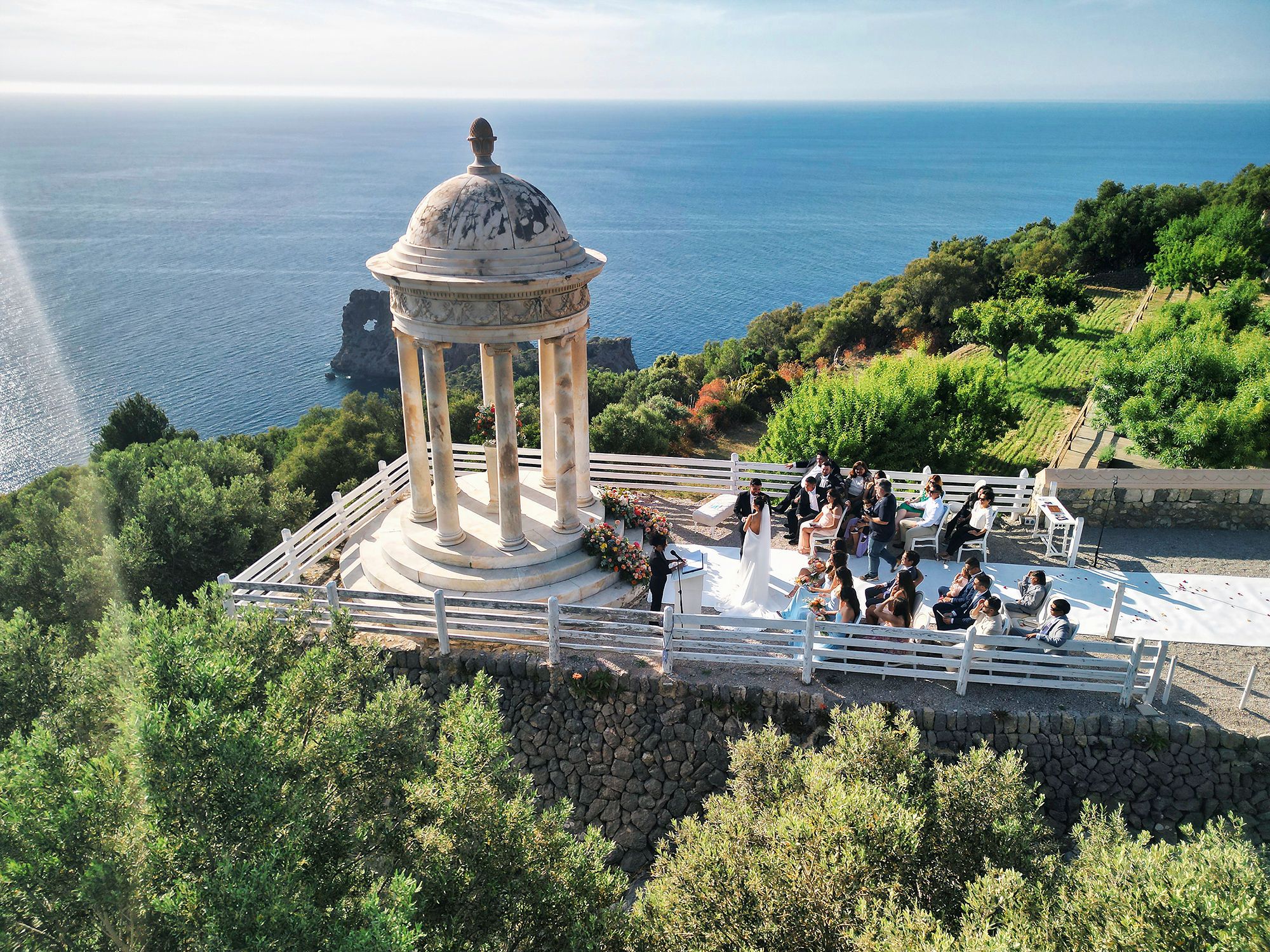 Clifftop destination wedding ceremony in Mallorca under the golden sunset skies with the Mediterranean Sea in the background
