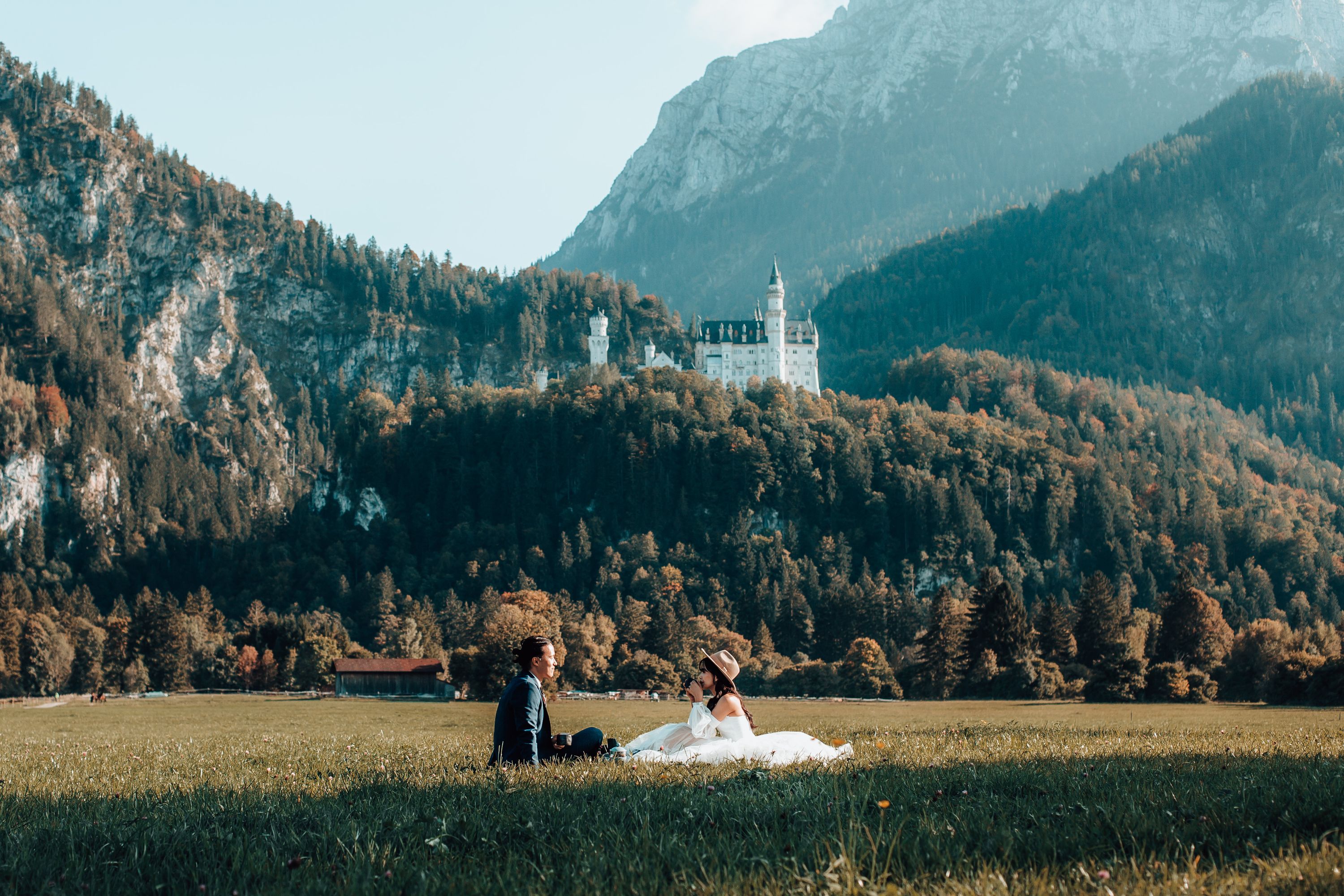couple having a picknick with a backdrop of mountains and a fairytale castle