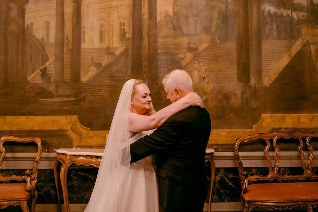 Bride and groom holding each other inside a room in a national monument during their vow renewal in Italy