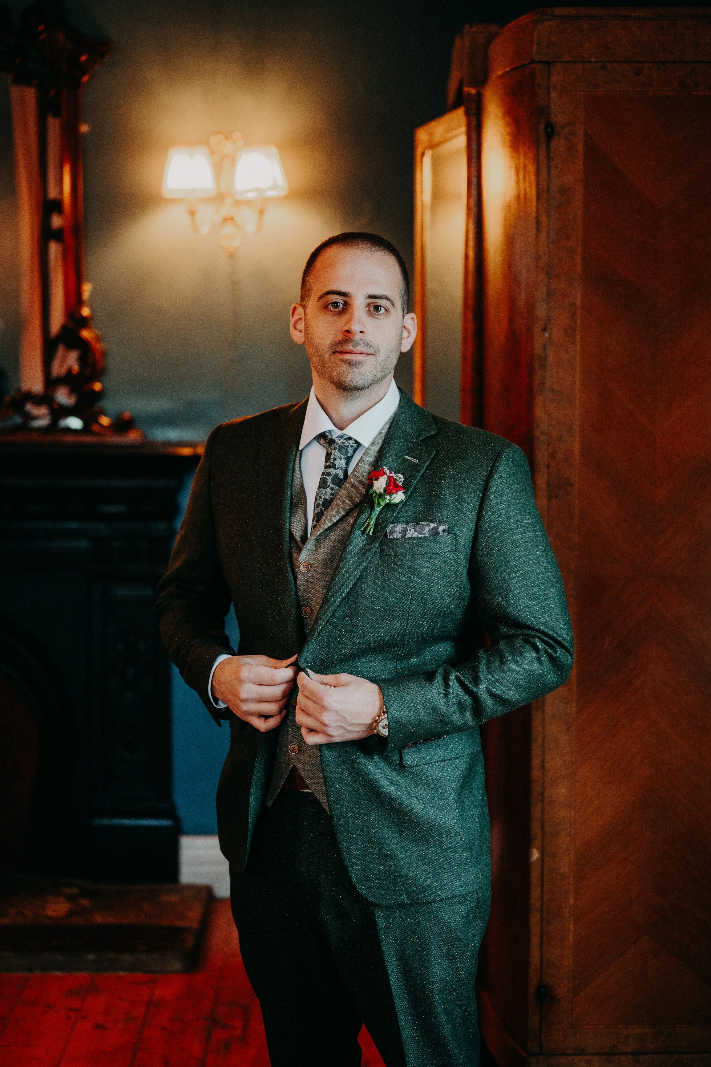 Groom adjusting his suit before a small wedding in Ireland inside a historic castle venue