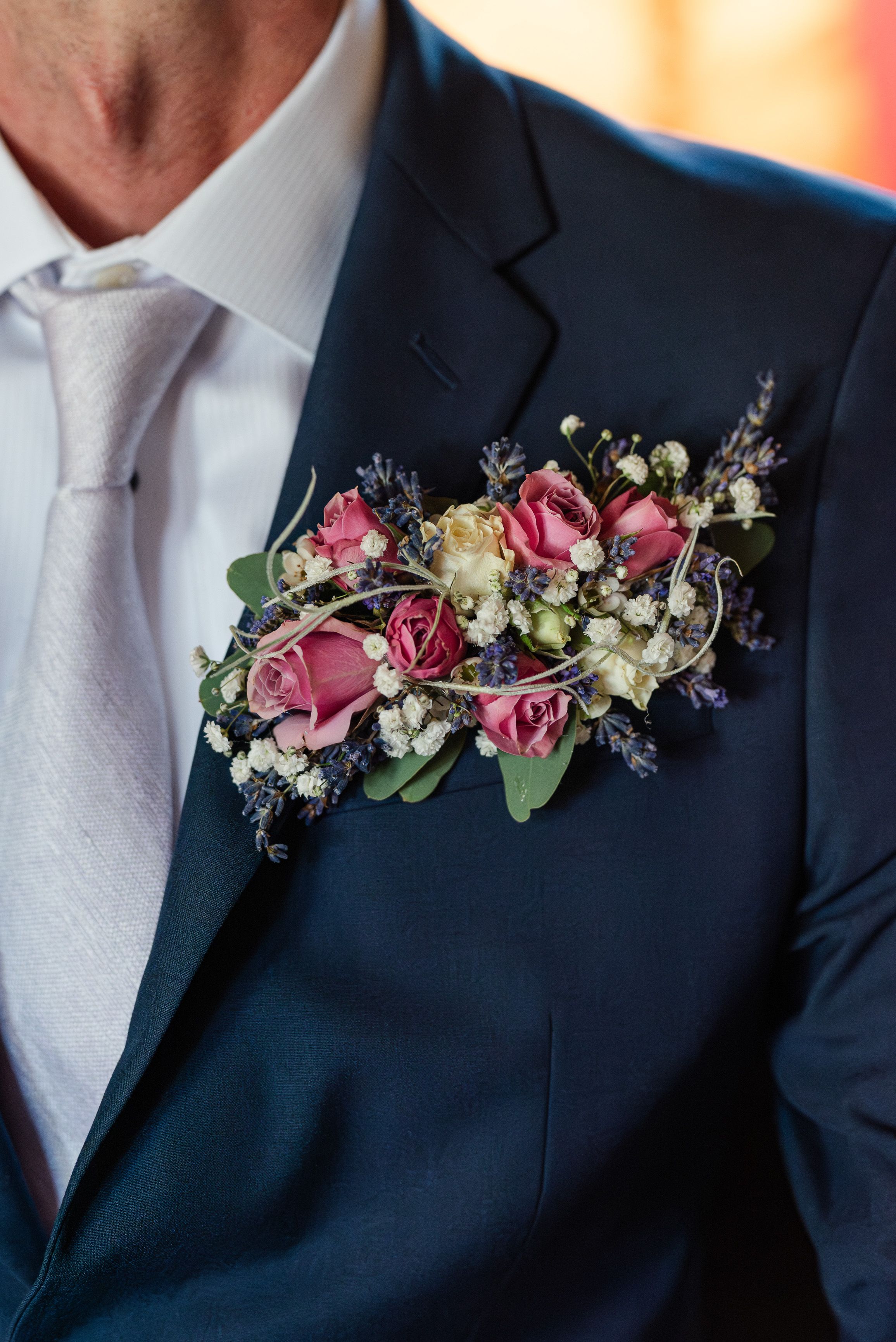 Groom's floral boutonniere with pink roses and lavender details during a intimate wedding in France