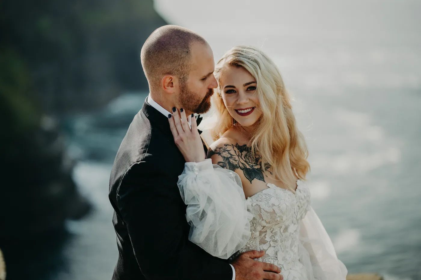 Bride and groom holding each other on a bright day atop the Cliffs of Moher