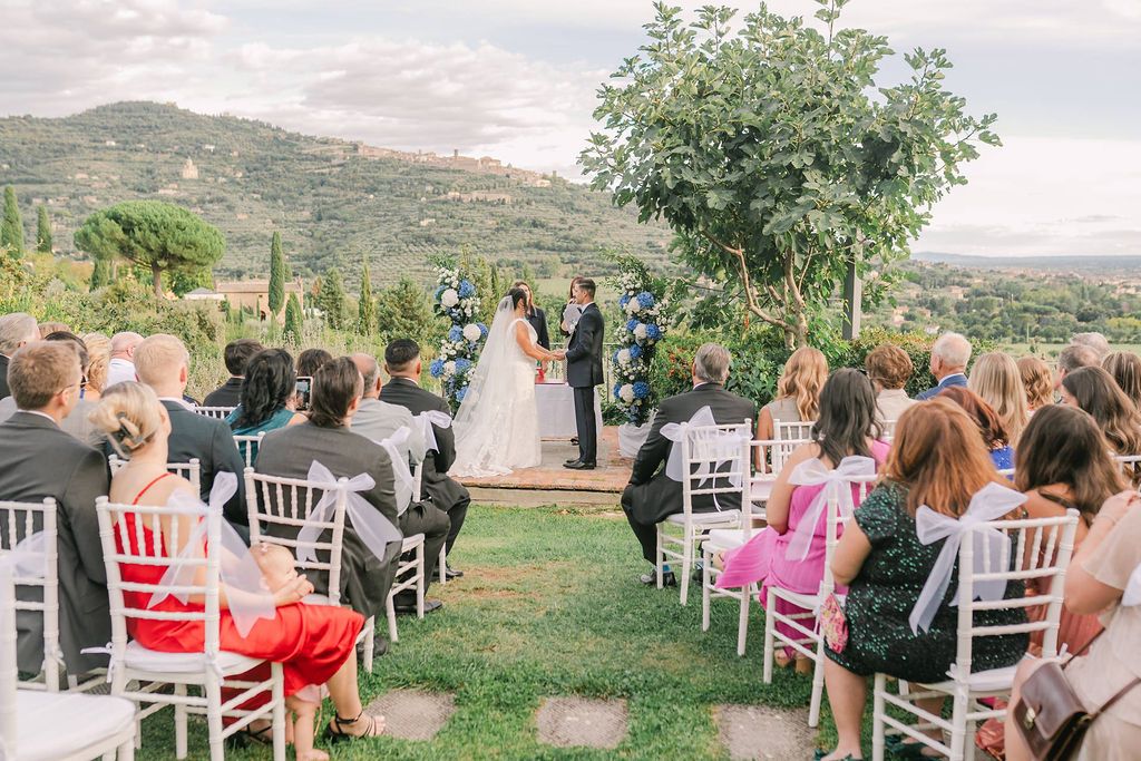 Bride and groom in front of their guests during the outdoor ceremony of their destination wedding in Tuscany, Italy
