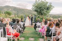Bride and groom in front of their guests during the outdoor ceremony of their destination wedding in Tuscany, Italy