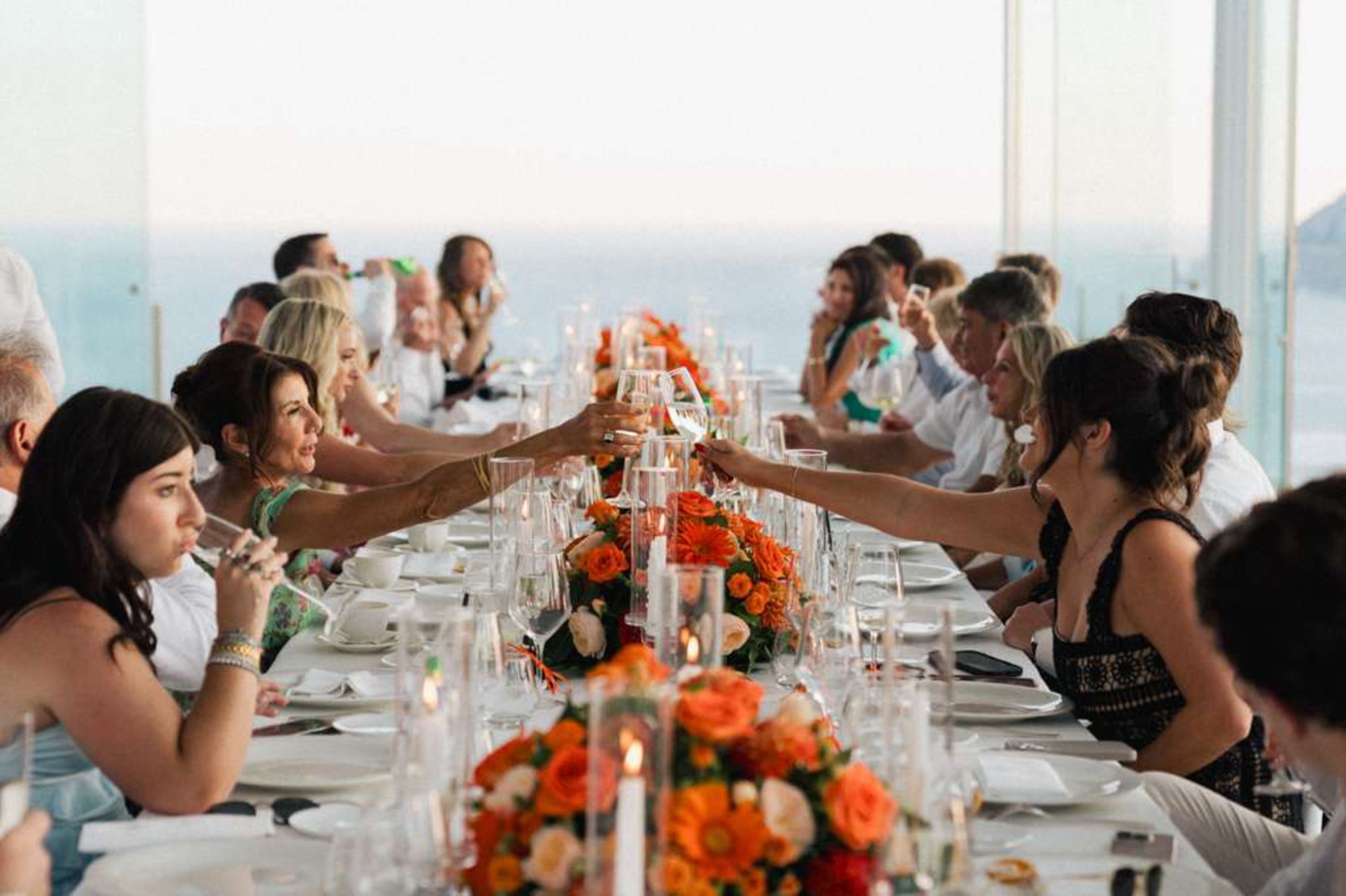 Guests raise a toast overlooking the sea during a small wedding in Italy with elegant floral tablescapes