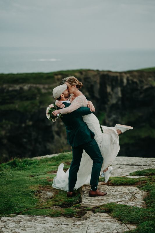 Bride and groom kissing atop Hags Head during their outdoor destination elopement in Ireland