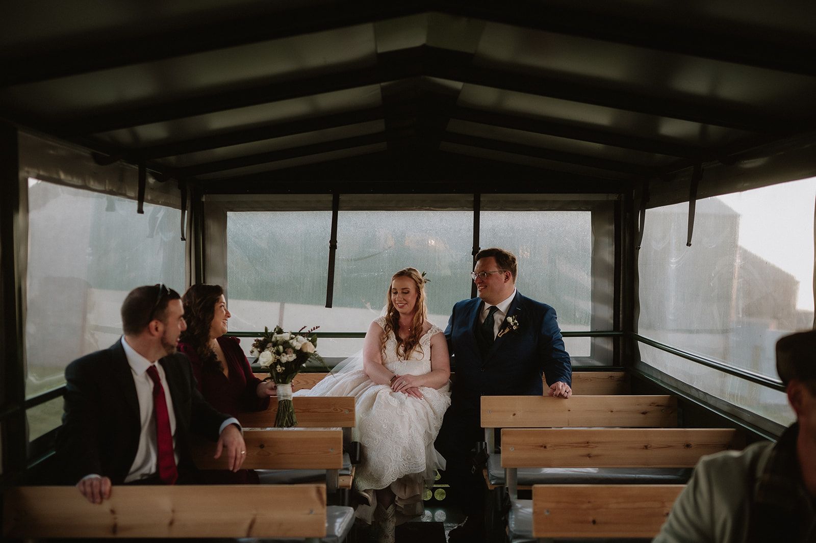 Bride and groom ride a coaster with their guests on the way to their clifftop ceremony spot