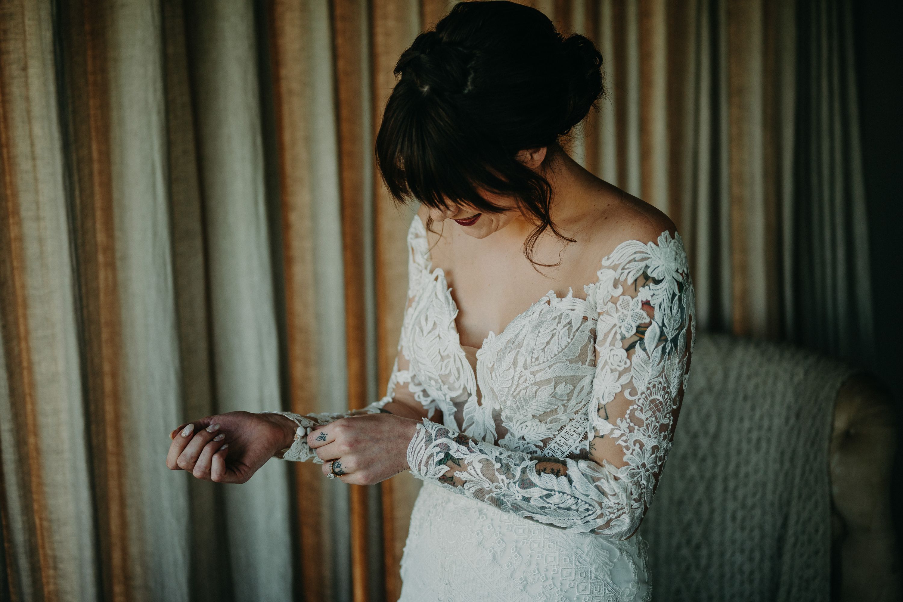 A bride fixing her dress inside a cottage in preparation for an intimate wedding in Ireland