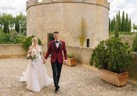 Bride and groom looks at the camera with smiles as they walked along the castle grounds when they tied the knot in Spain