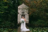 Newlyweds in the middle of a boardwalk over a lake, surrounded by trees having a photoshoot for their small wedding in Ireland