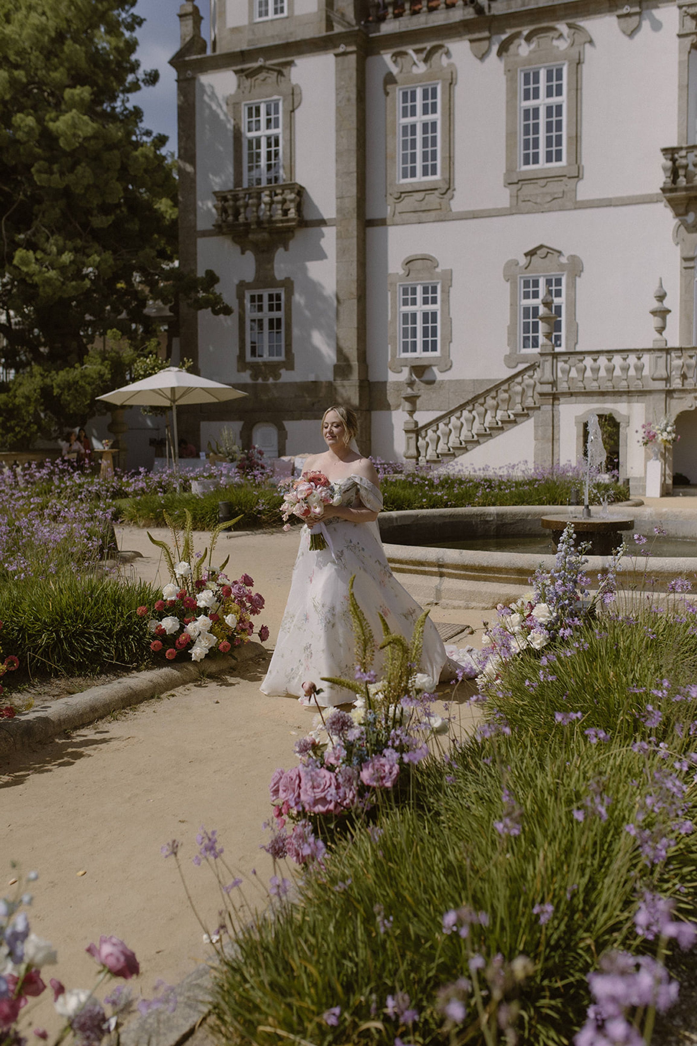 Bride walking through colorful gardens with her bouquet at a small wedding in Portugal