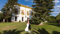 Bride and groom kiss in front of an elegant farmhouse in Cadiz surrounded by trees when they got married in Spain