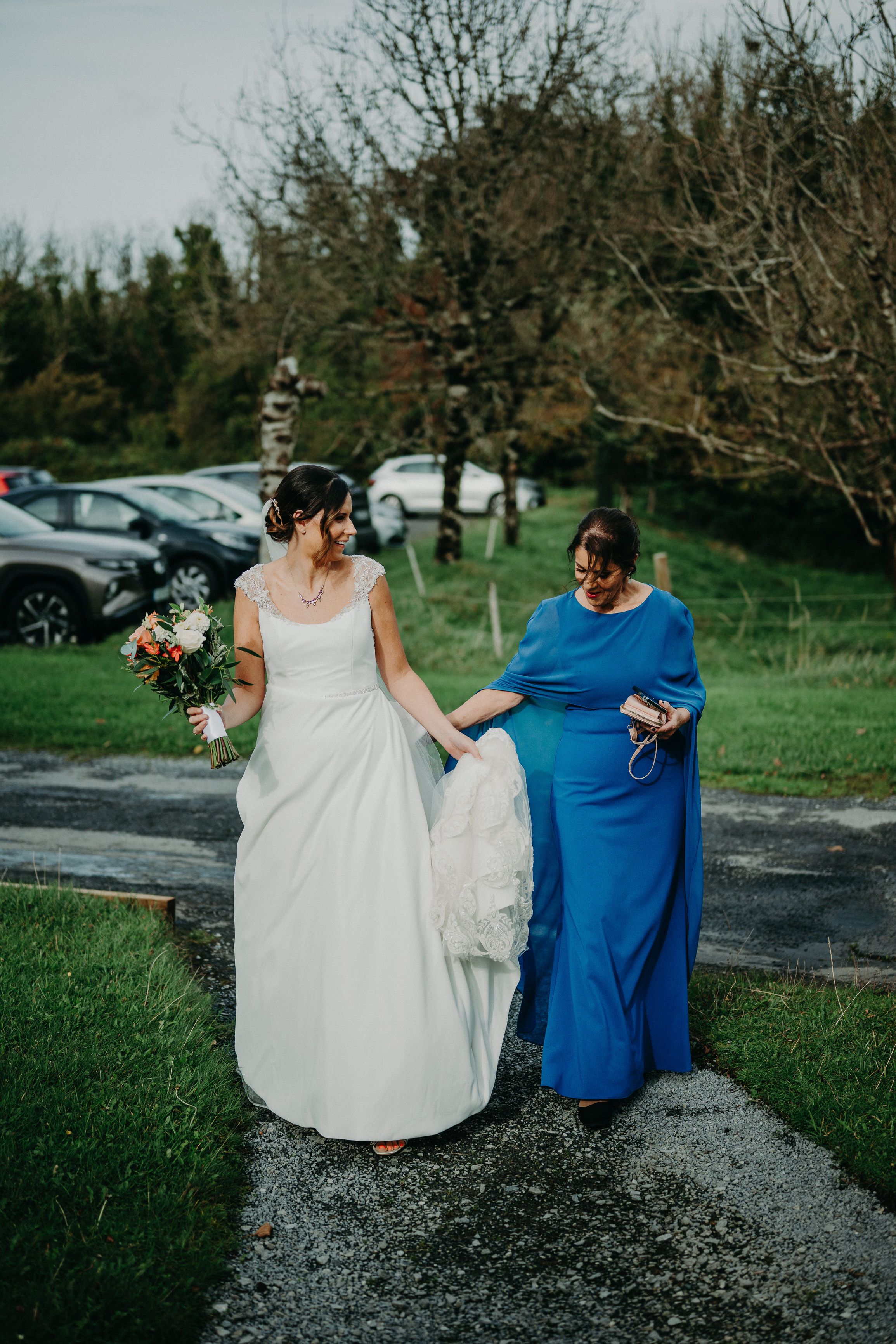Bride walks toward the ceremony holding her bouquet before a small wedding in Ireland at a castle venue.