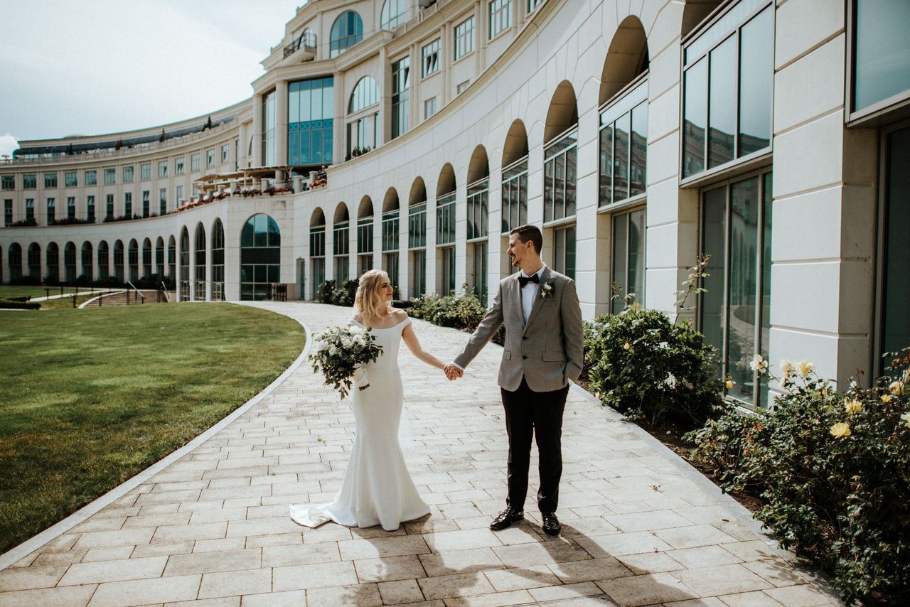 Newlyweds walk along a path in front of a luxury castle hotel after the ceremony of their destination wedding in Ireland