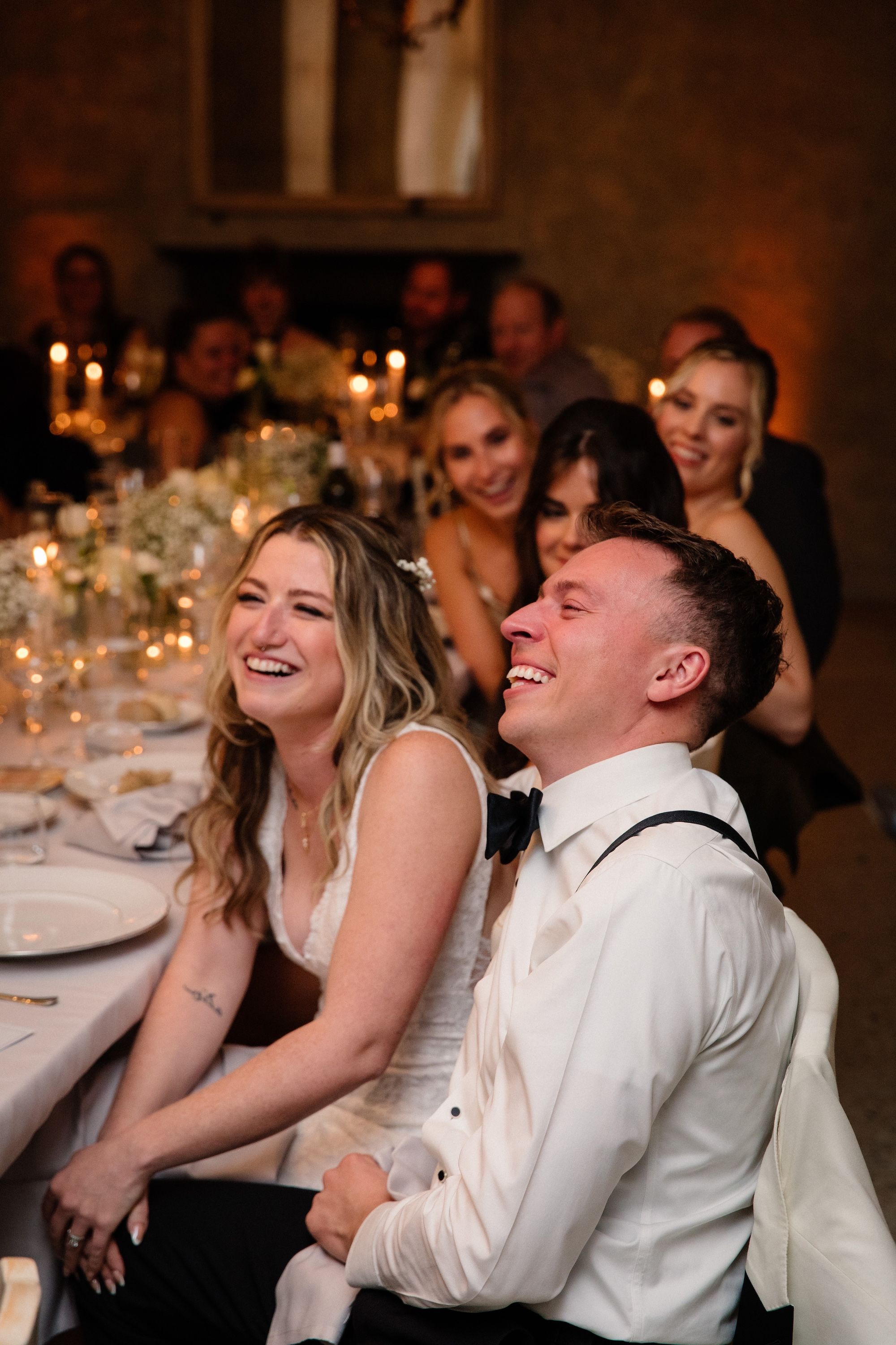 Bride and groom laughing while a guest gives a speech during the reception of their vow renewal in Italy 