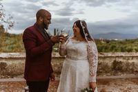Bride and groom drinking wine on the terrace of their venue with the rolling hills of Tuscany in background