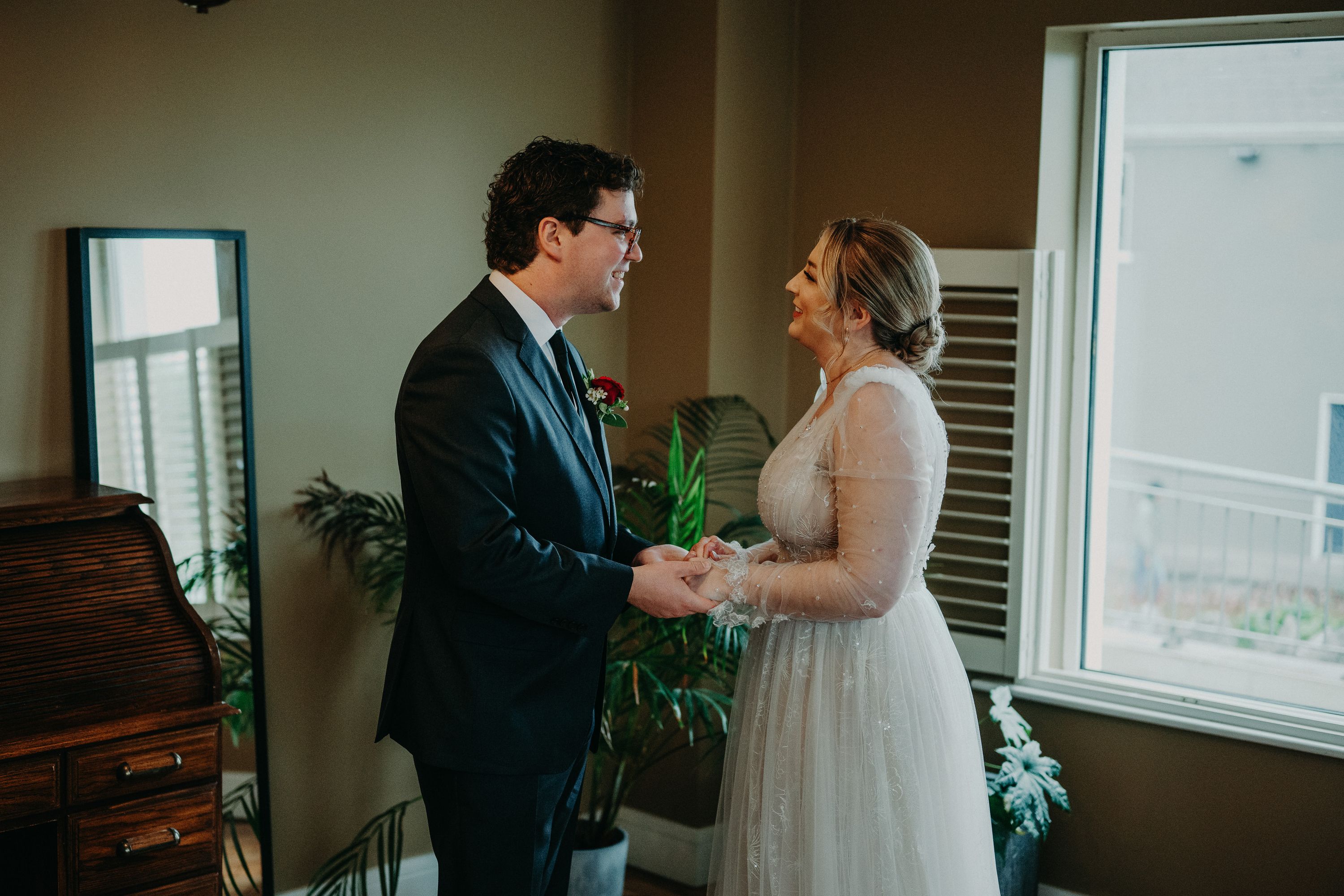 Bride and groom sharing an emotional first look moment at a small wedding in Ireland, holding hands by a window