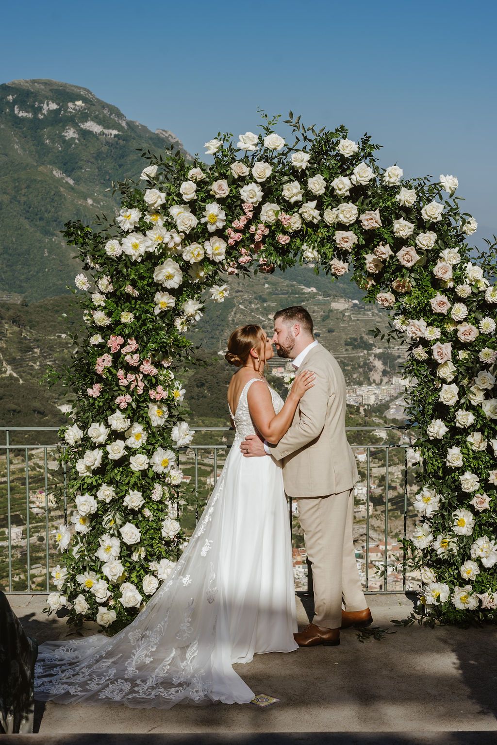 Bride and groom kissing in an outdoor ceremony of their wedding in Italy with the Amalfi Coast views in the background