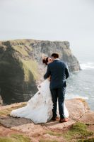 Bride and groom kiss on a cliff at Hag's Head when getting married in Ireland