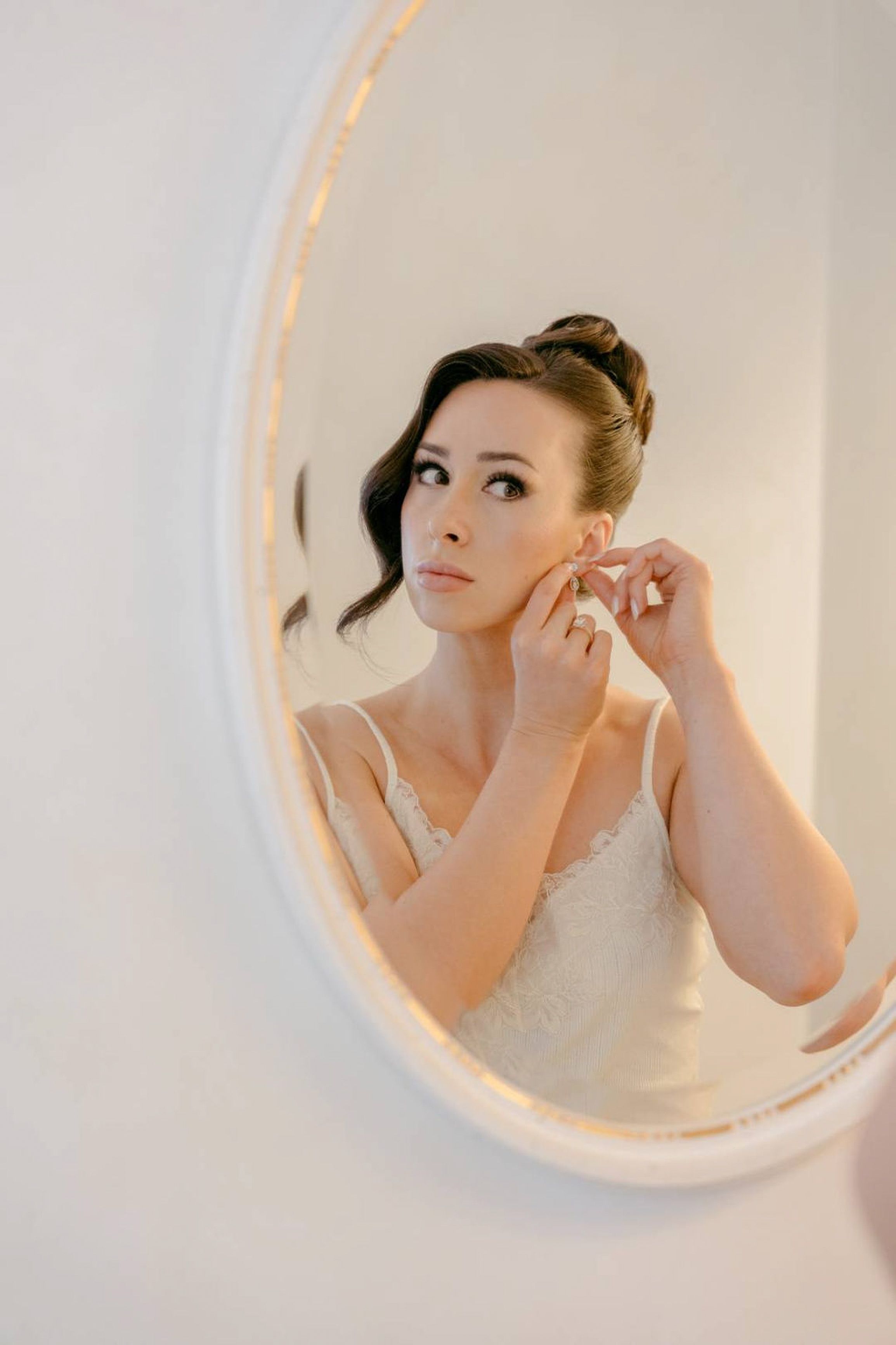 Bride fastening her earrings in a mirror during bridal preparations for an intimate wedding in Italy