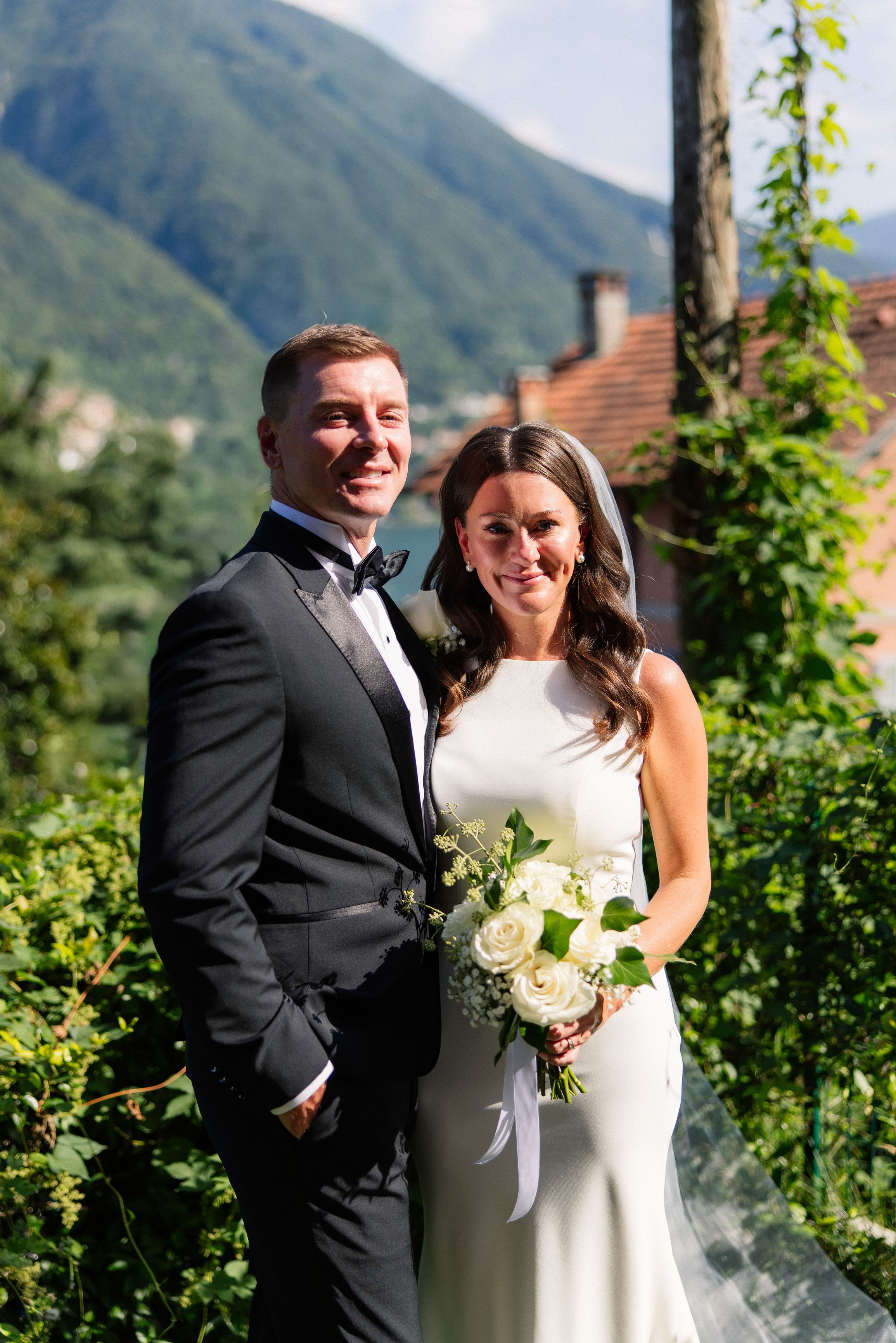 Bride and groom portrait with bouquet and mountain backdrop at a small wedding in Italy