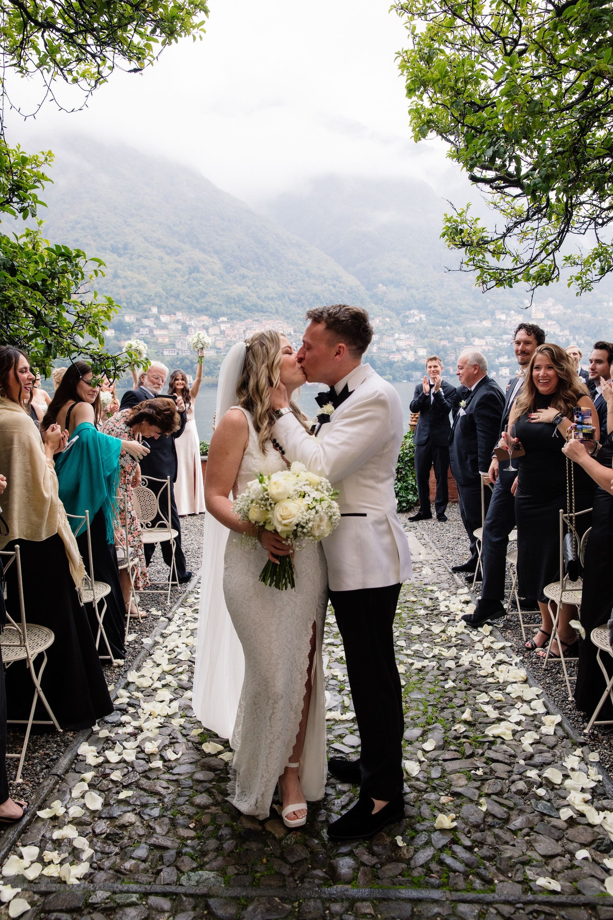 Newlyweds kissing amidst their guests after the outdoor ceremony of their vow renewal in Italy