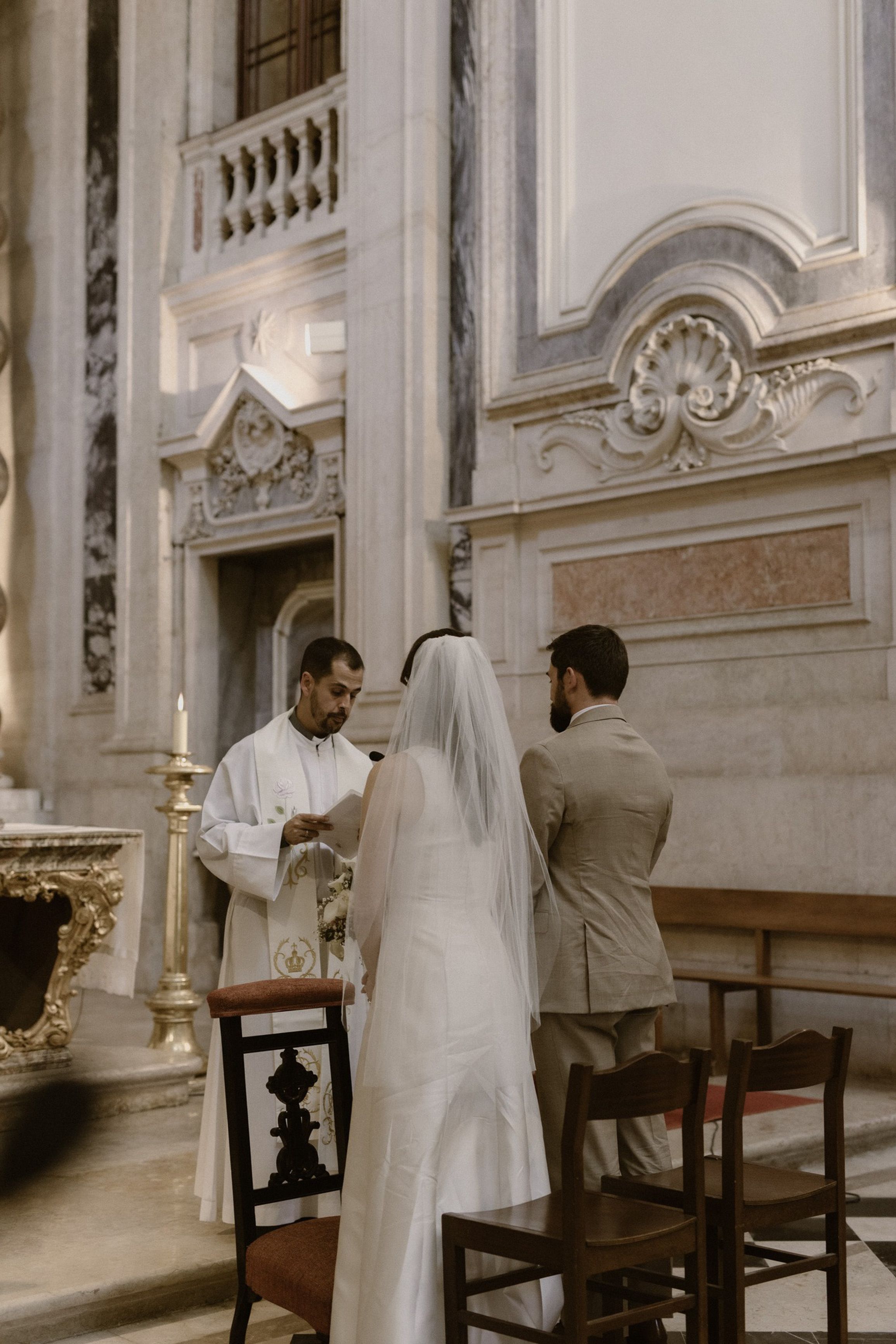 Bride and groom participating in a church ceremony during an intimate wedding in Portugal with elegant historic interiors