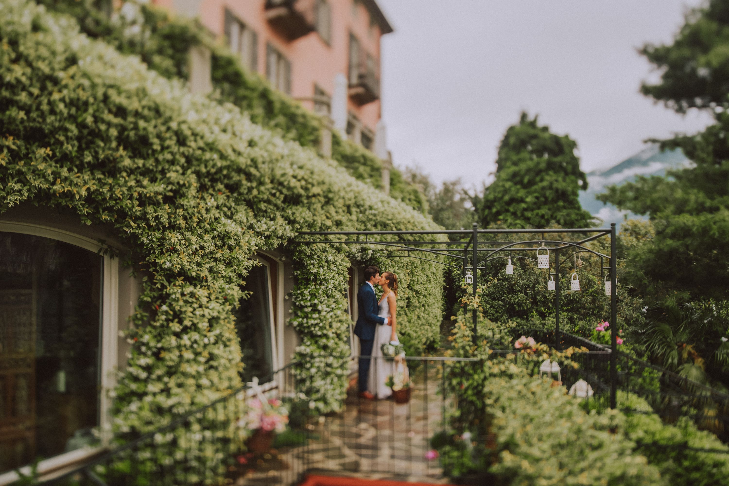 Bride and groom kissing in the middle of an estate with lush greenery in the background during their elopement in Italy