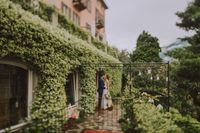 Bride and groom kissing in the middle of an estate with lush greenery in the background during their elopement in Italy