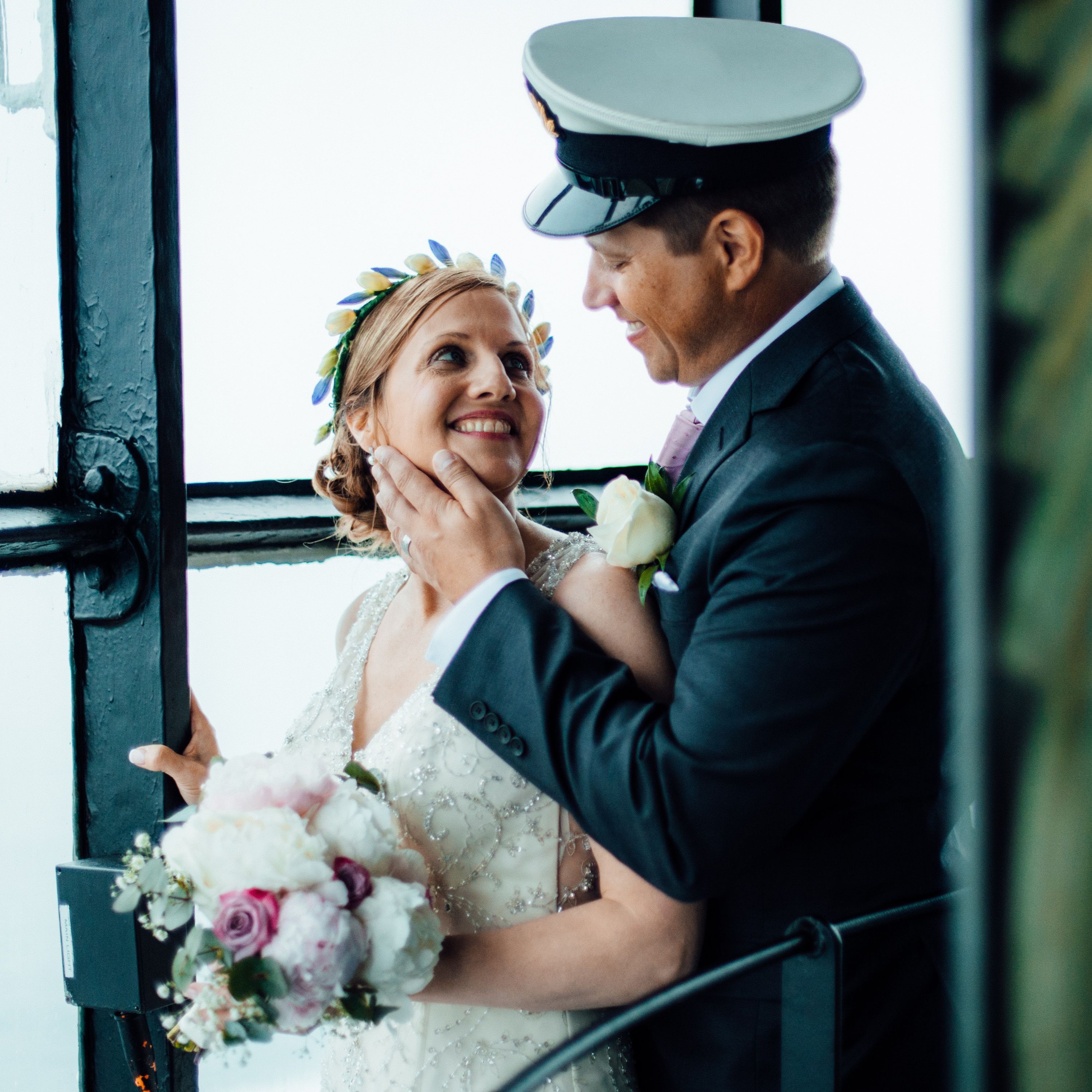 Groom wearing a nautical sailor’s attire holding his bride’s chin romantically during their elopement in Ireland
