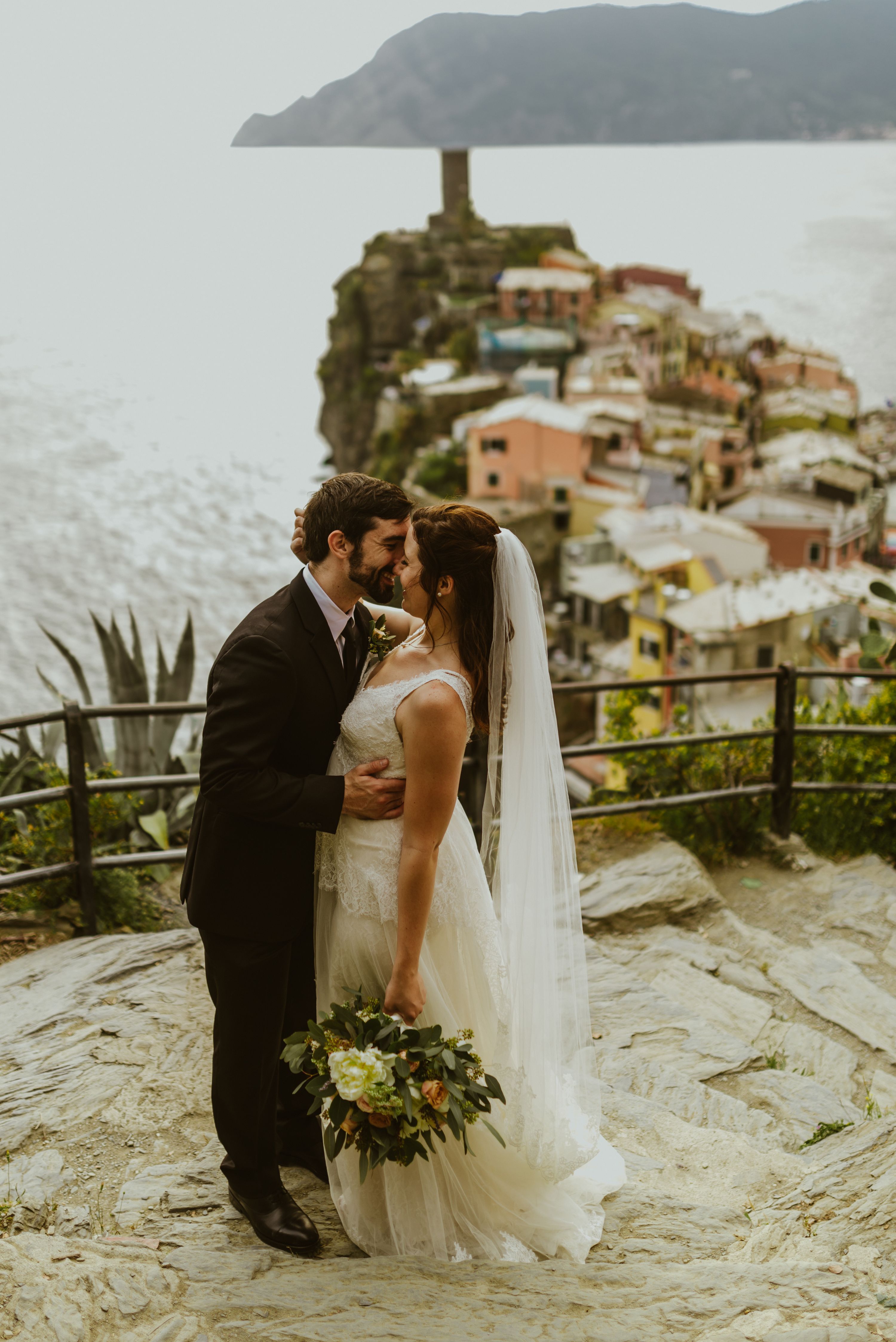 Bride and groom kissing during destination wedding in Italy with the iconic Cinque Terre scenery in the background