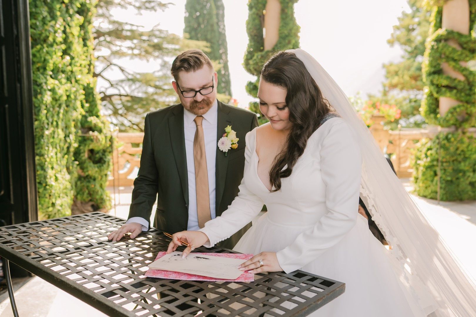 Newlyweds looking at a document after the outdoor ceremony of their destination wedding in Italy along Lake Como