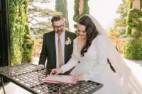 Newlyweds looking at a document after the outdoor ceremony of their destination wedding in Italy along Lake Como