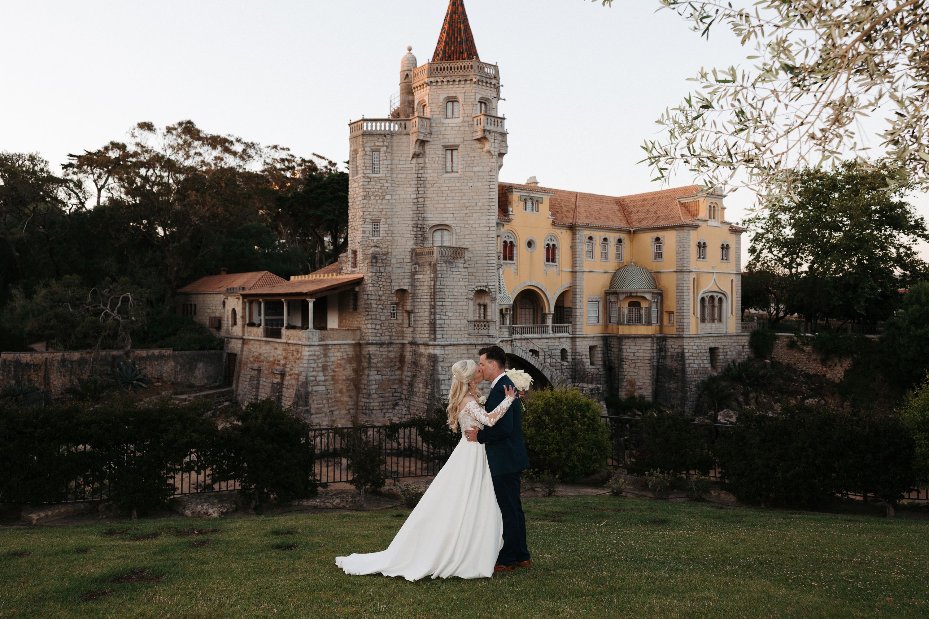 Newlyweds kissing each other during the photoshoot of their destination wedding in Portugal with a tall castle at the back