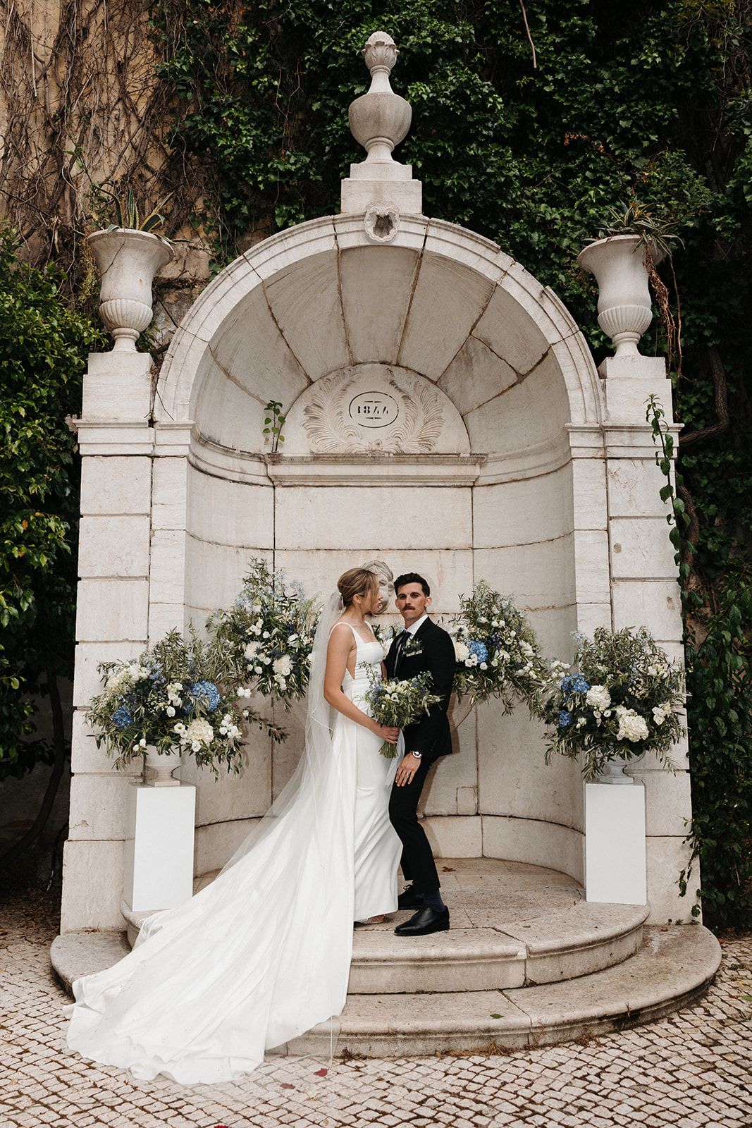 Bride and groom under a stone gazebo for the ceremony of their destination wedding in Portugal