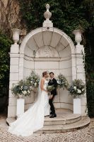Bride and groom under a stone gazebo for the ceremony of their destination wedding in Portugal