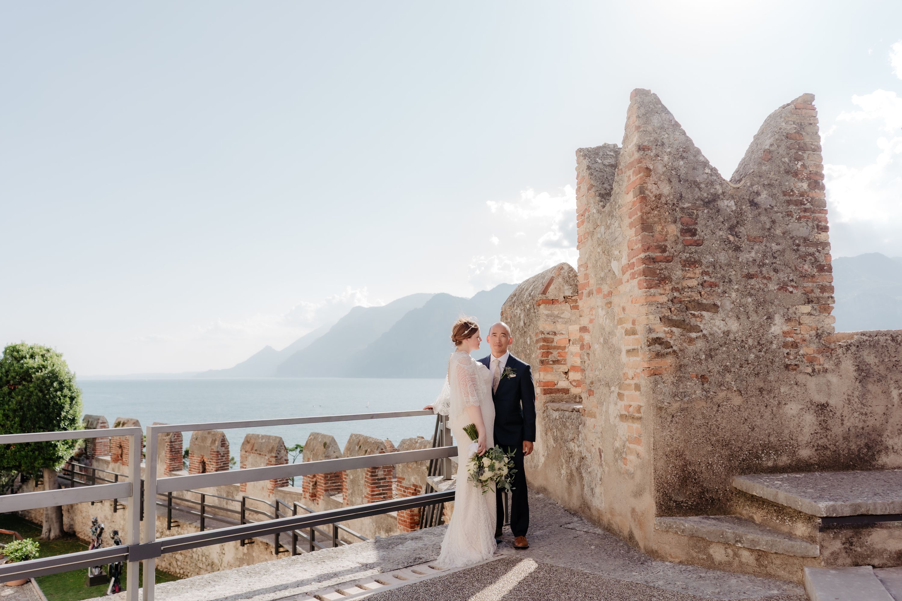 Couple looking afar with a historic castle in Italy and Lake Garda in the background