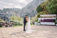 Bride and groom holding each other with a view of Sicily, Italy, and a flowerbox in the background