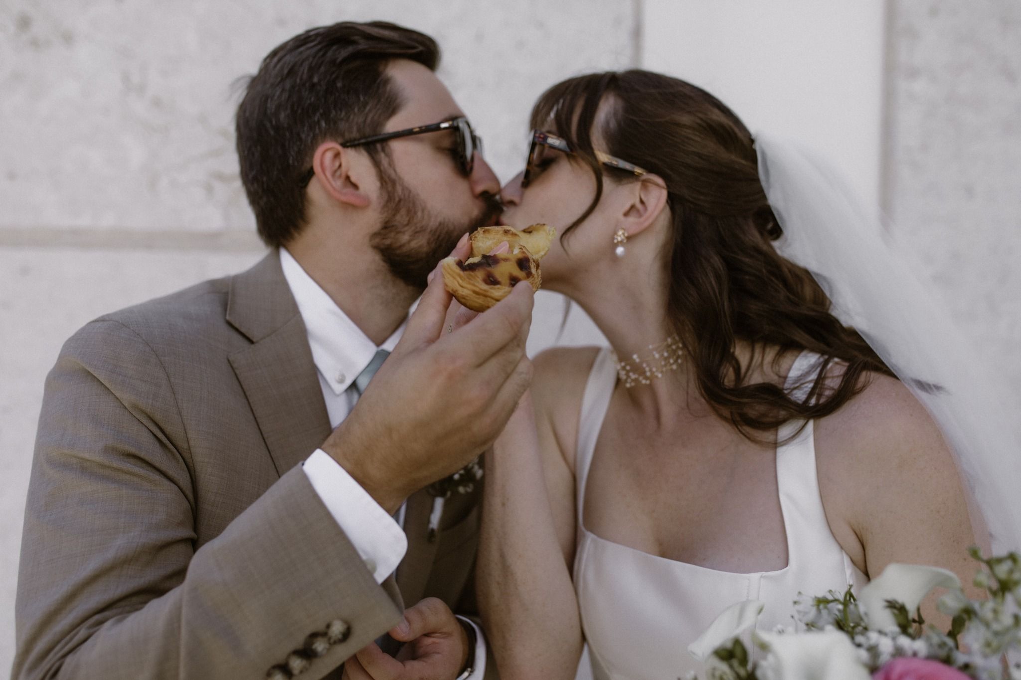 A bride and a groom in summer eating pastéis de nata