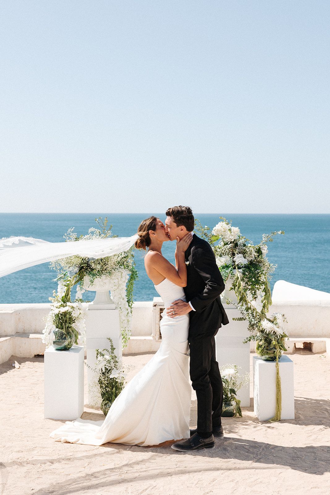Newlyweds standing in front of their wedding arch on the cliffs after the ceremony of their Portuguese destination wedding