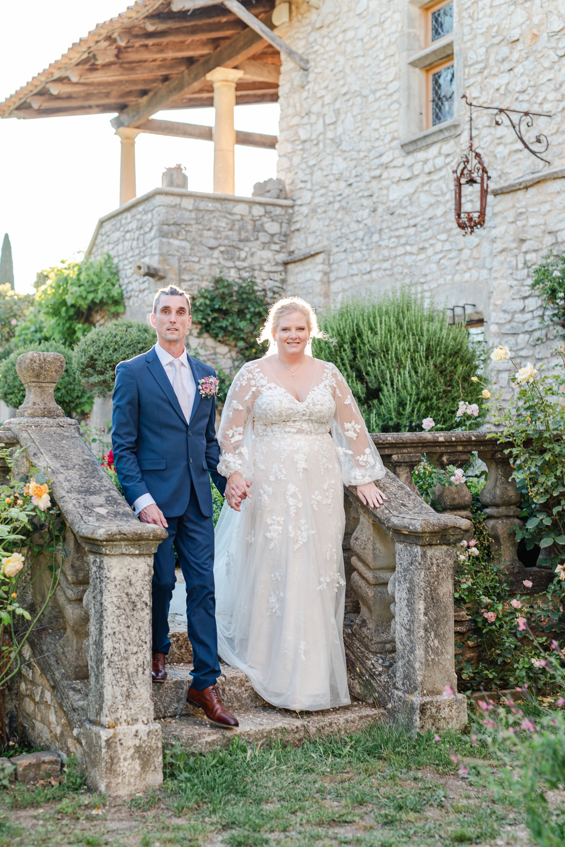 Newlyweds posing on stone steps outside a countryside venue during a small wedding in France