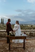 Bride and groom hold hands during their elopement ceremony in Tuscany on the terrace of the medieval villa where they got married